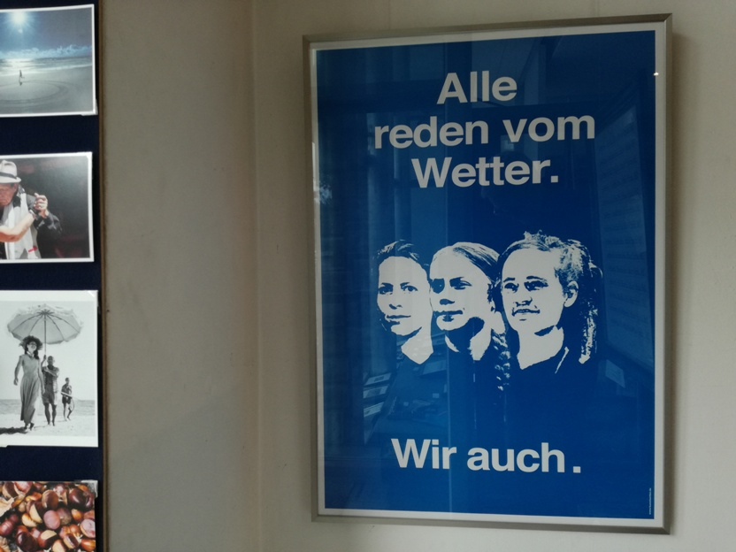 Plakat von AC Klarmann "Alle reden vom Wetter.      Wir auch." (blau) Die dargestellten Frauen sind von rechts nach links: Judith Ellens (Sozial-Unternehmerin), Greta Thunberg (Klima-Aktivistin) und Carola Rackete (Kapitänin und Seenotretterin)
Das Plakat ist direkt gerahmt in einem Roggenkamp-Wechselrahmen Alu K natur. (86x61cm)