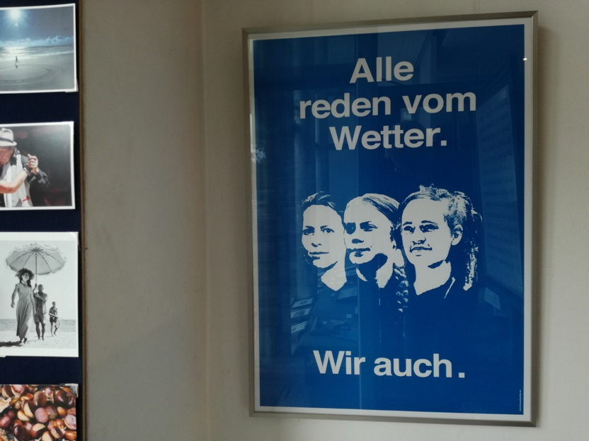 Plakat von AC Klarmann "Alle reden vom Wetter.      Wir auch." (blau) Die dargestellten Frauen sind von rechts nach links: Judith Ellens (Sozial-Unternehmerin), Greta Thunberg (Klima-Aktivistin) und Carola Rackete (Kapitänin und Seenotretterin)
Das Plakat ist direkt gerahmt in einem Roggenkamp-Wechselrahmen Alu K natur. (86x61cm)